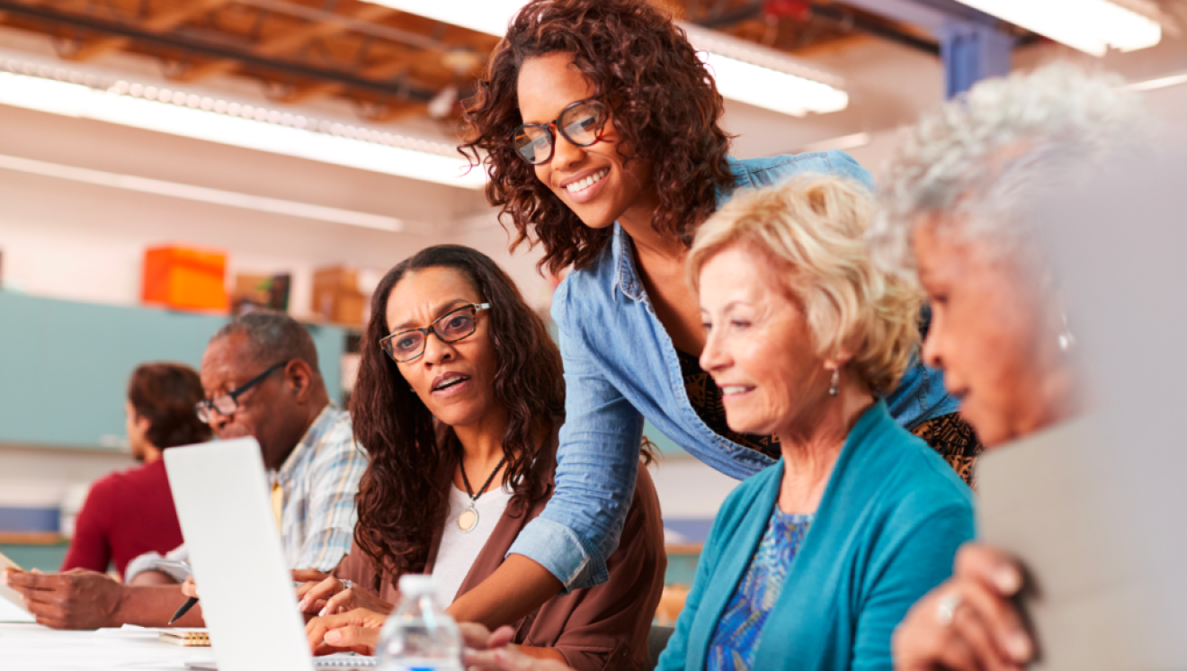 A facilitator leans in between two adult learners