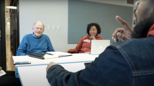 A group of three adults sit around a table in conversation